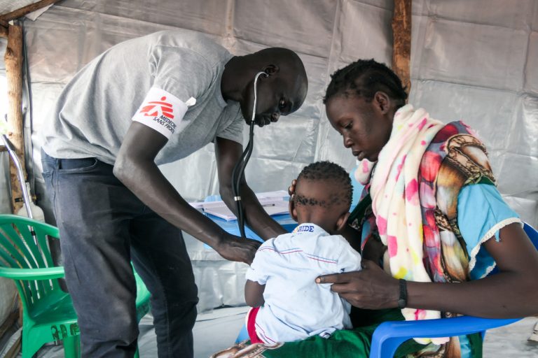MSF Clinical Officer Chuol Hoth examines a child at the MSF Mobile Clinic in Bulukat transit centre, Upper Nile State South Sudan. The Bulukat transit centre hosts thousands of returnees living under temporary shelters. Their living conditions are deplorable as the now muddy terrain heightens their life with onset of diseases