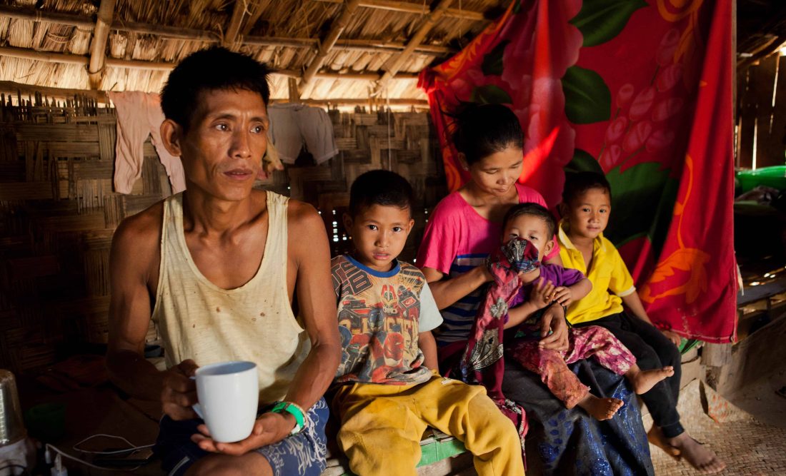 Thongsei Lupho (44) and his wife Mary and some of their seven children. His son sitting next to him is also HIV-positive and receives treatment from the MSF clinic in Moreh. Thongsei is HIV positive and has been a patient at the MSF Clinic in Moreh since 2012. 
Thongsei used to work in charcoal and cultivation. Since he contracted HIV, his health has deteriorated and he is no longer able to do manual labour. He has seven children; the oldest is 17 years old and the youngest one 14 months old. Mary takes care of the children. Thongsei contracted HIV through drug use: Lupho had used drugs in the past to gain social acceptance in an area where tribal tensions had fostered a lack of trust amongst people.
He first visited the MSF clinic because he thought he had TB. By that point, he had stopped taking drugs and married. He was in fact diagnosed HIV-positive. His failing strength meant he was no longer able to work. He was afraid of discrimination and isolated himself. He thought he could no longer mingle with other people in public spaces. His eldest daughter, Lamknohat, and several of his other children are also HIV-postive. Lamknohat feels ashamed and doesn’t want other people to know.